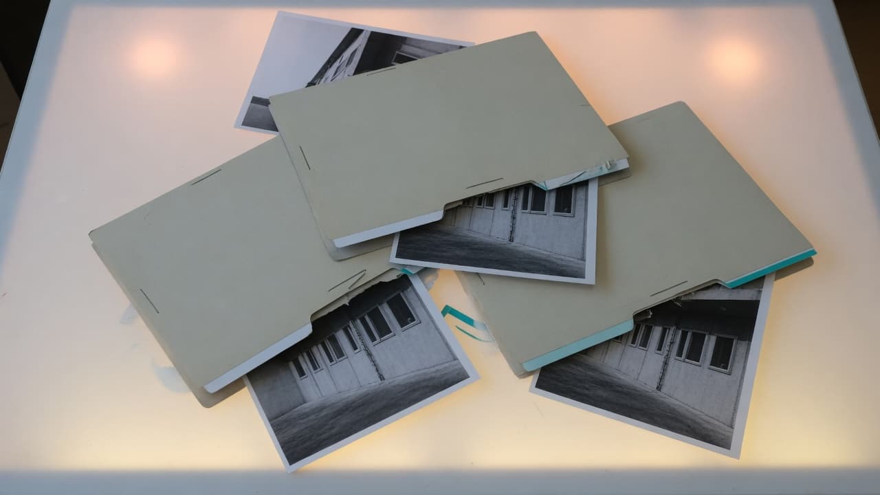 Vier Mappen mit denselben Architekturfotos, unordentlich auf einem Leuchttisch gestapelt